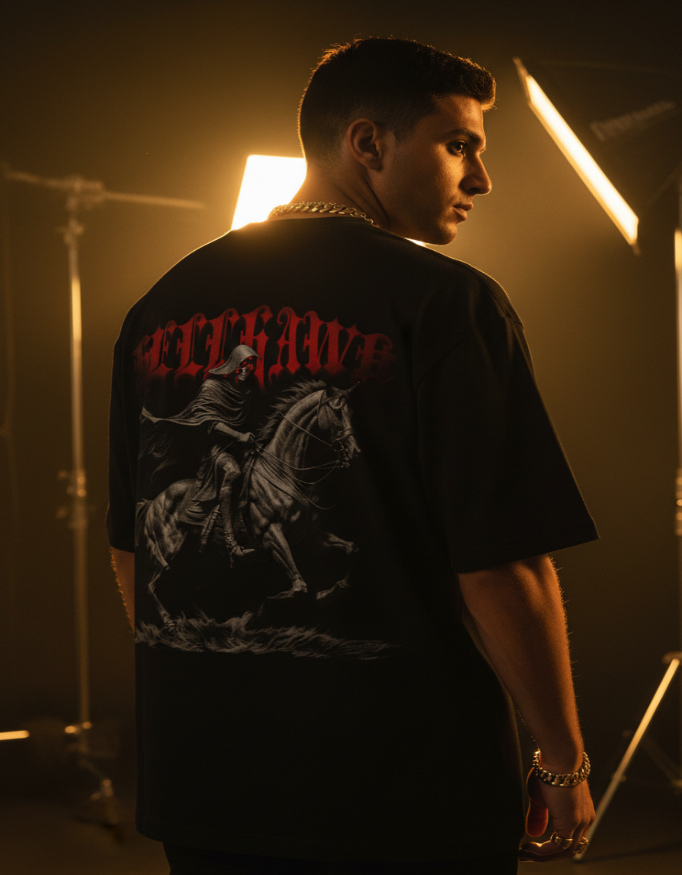 Person wearing a black t-shirt with graphic design and text, standing in a studio setting.